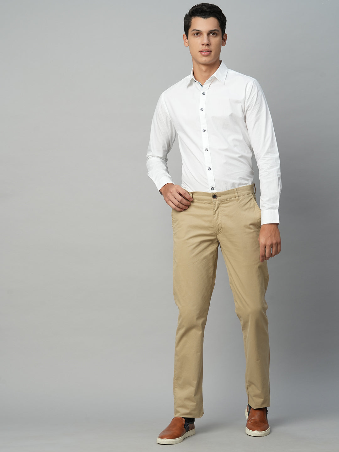 A Young Attractive Fellow in a White Shirt and Beige Pants Looks in the  Distance on a Light Blurred Background Stock Image  Image of cheerful  arms 97962823